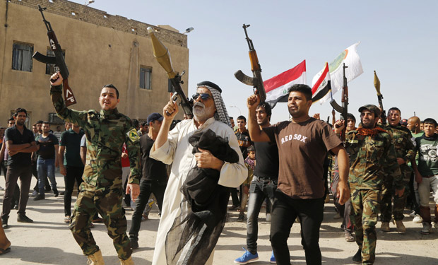 Volunteers, who have joined the Iraqi Army to fight against predominantly Sunni militants, carry weapons during a parade in the streets in Baghdad's Sadr city