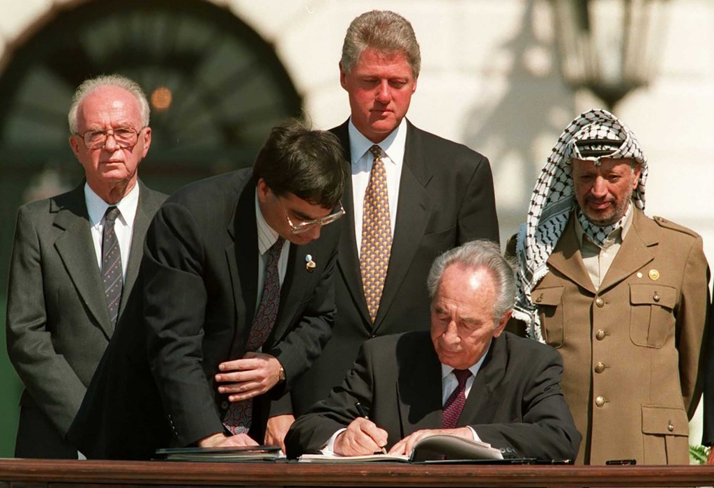 Peres, junto con el líder palestino Yasser Arafat firmando el histórico acuerdo de Oslo en Washington, DC en 1993. Detrás de ellos, oblo observan el entonces Primer Ministro de Israel, Rabin, y el presidente estadounidense, Bill Clinton