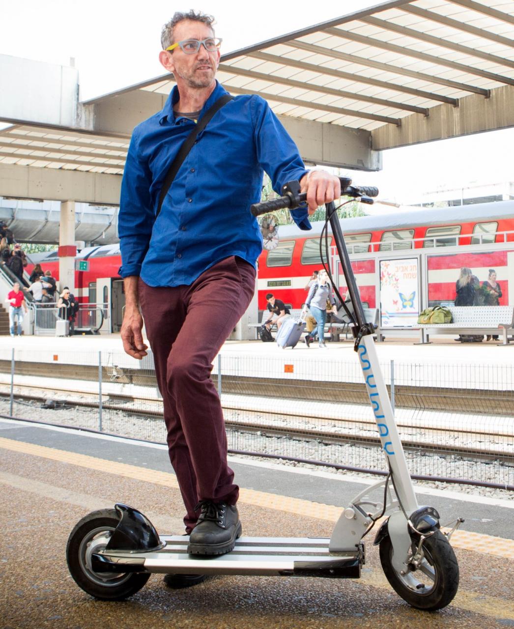 El diseñador de Inokim, Nimrod Sapir, con una de sus scooters en una estación de tren en Israel. Foto de Shlomi Yosef. 