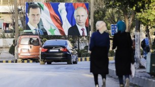 Syrians walking past a giant poster of Syrian President Bashar Assad (L) and his Russian counterpart Vladimir Putin (R) in the northern Syrian city of Aleppo, March 9, 2017. (AFP Photo/Joseph Eid/ File)